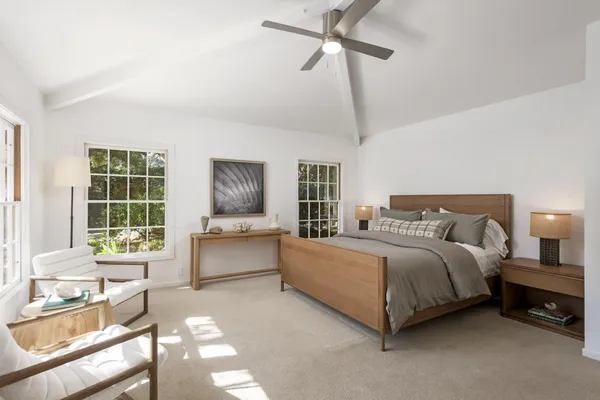 a spacious bedroom with a bed and a dresser next to a window