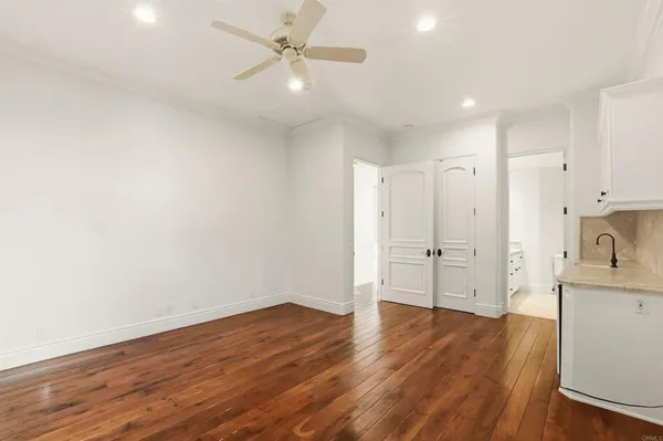 an empty room with wooden floor chandelier and windows