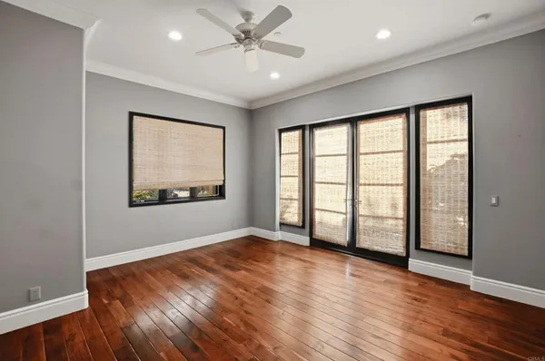 a view of empty room with wooden floor and a window