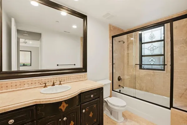 a bathroom with a granite countertop tub sink and mirror