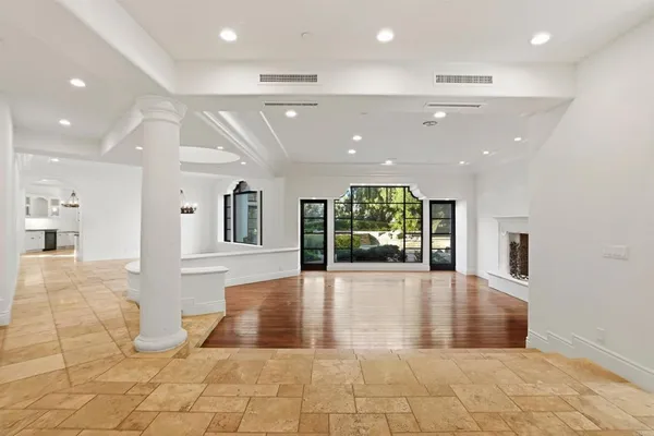 a view of a big room with wooden floor and windows