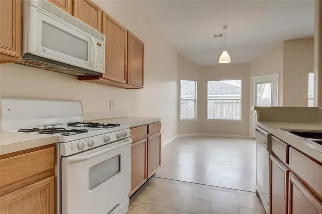 a kitchen with granite countertop a stove top oven microwave and cabinets