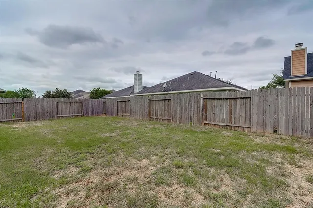 a view of a house with backyard and wooden fence