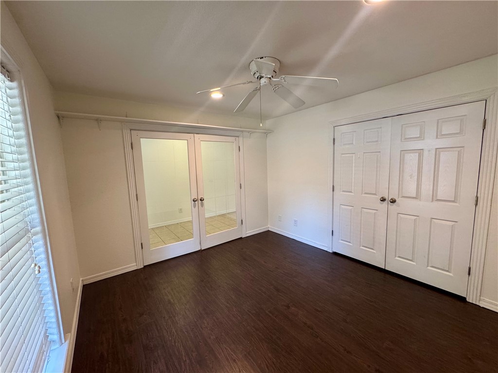 Room featuring dark wood-finish flooring, white walls, and a ceiling fan