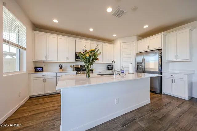 a large white kitchen with kitchen island a sink a center island and stainless steel appliances