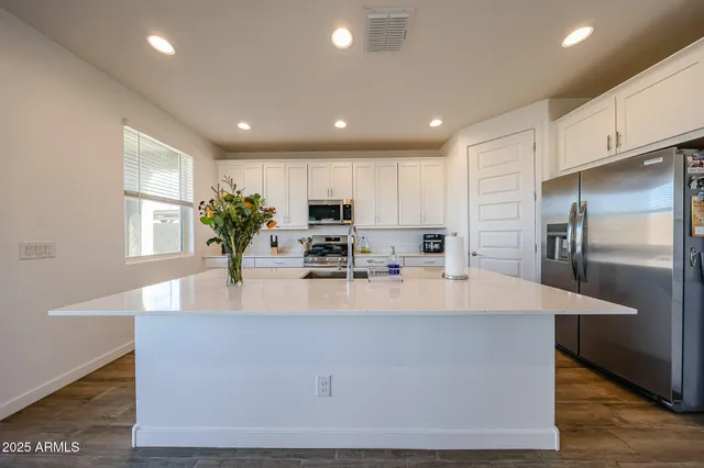 a large kitchen with kitchen island a large counter top stainless steel appliances and cabinets