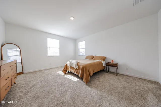 a bed sitting in a spacious bedroom next to a window
