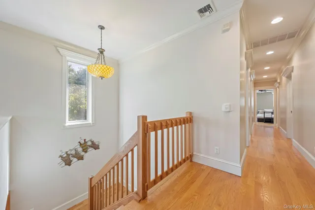 a view of a hallway to a bedroom with wooden floor and windows