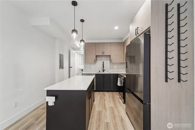 a kitchen with kitchen island a counter top space a sink stainless steel appliances and cabinets