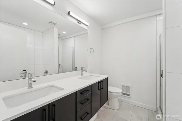 a bathroom with a double vanity sink toilet and a mirror