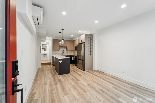 a view of a kitchen with kitchen island wooden floor center island and stainless steel appliances