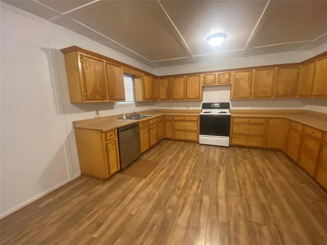 a kitchen with wooden floors and white stainless steel appliances