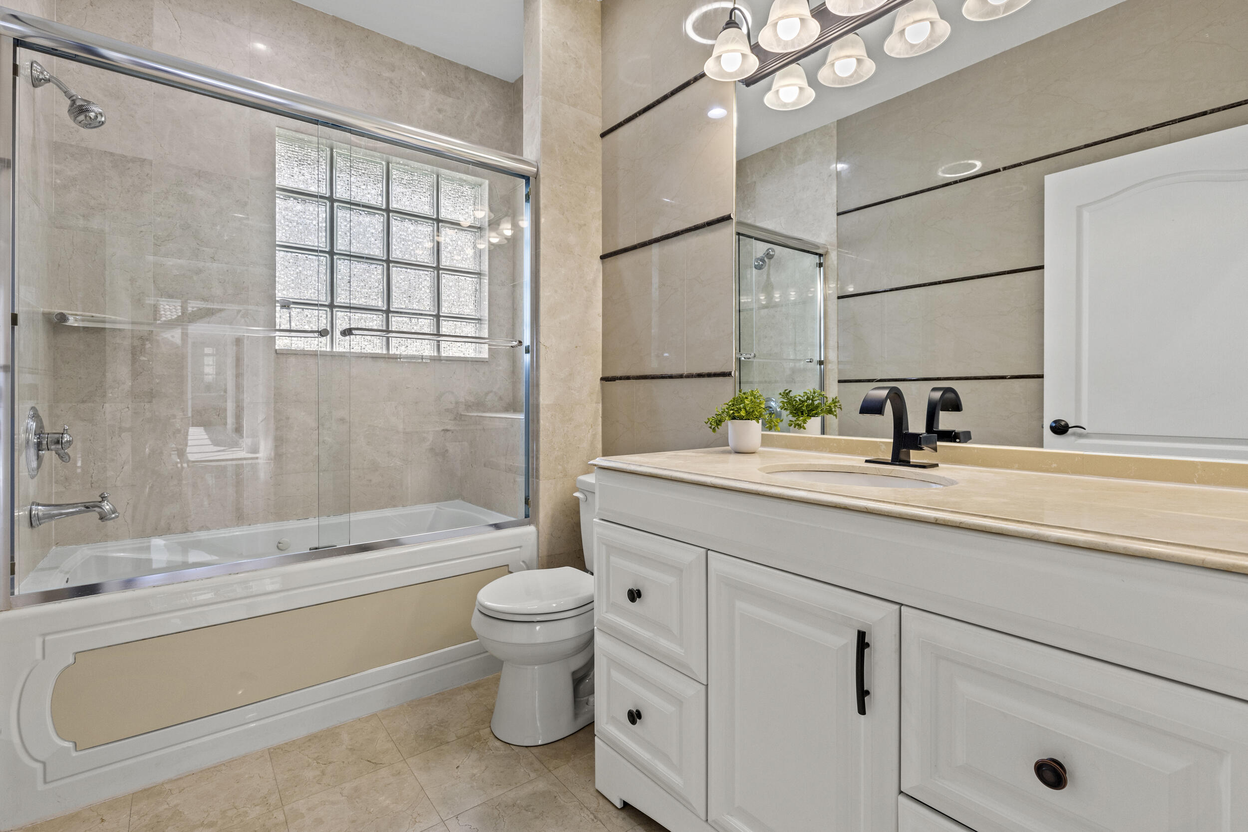 10431 Stonebridge Boulevard Boca Raton, FL 33498 - Photo 31 of 52 a bathroom with a granite countertop sink a toilet a mirror a vanity and bathtub