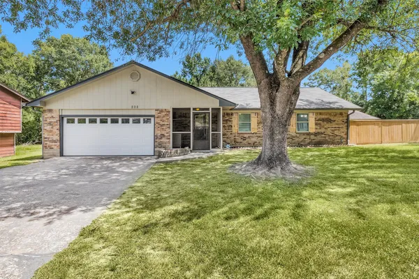 a view of a house with a yard and large tree
