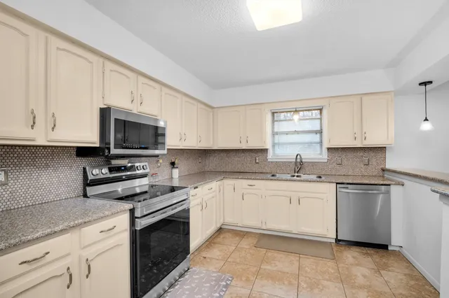 a kitchen with stainless steel appliances granite countertop white cabinets a sink and dishwasher a stove top oven with wooden floor