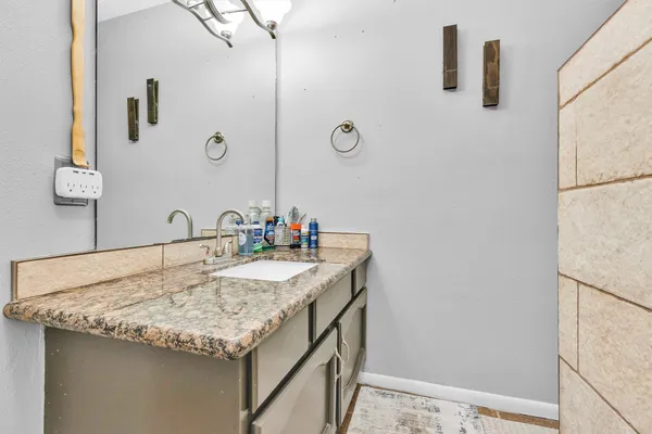 a bathroom with a granite countertop sink and a mirror