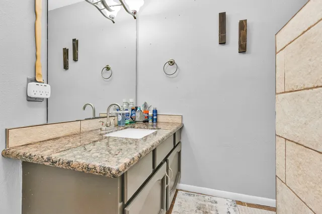 a bathroom with a granite countertop sink and a mirror