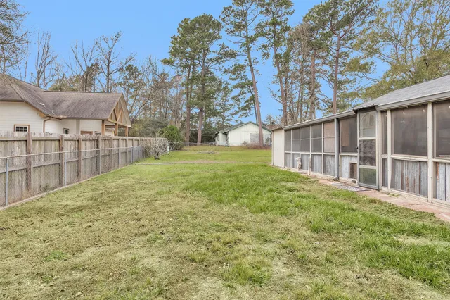 a view of backyard with wooden fence and large trees