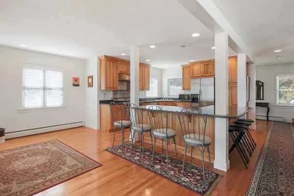 a kitchen with stainless steel appliances granite countertop a refrigerator oven stove a dining table and chairs with wooden floor