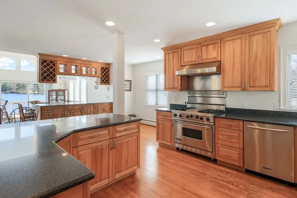 a kitchen with stainless steel appliances granite countertop wooden cabinets a stove a sink and a large window