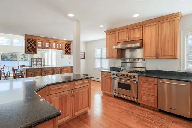 a kitchen with stainless steel appliances granite countertop wooden cabinets a stove a sink and a large window