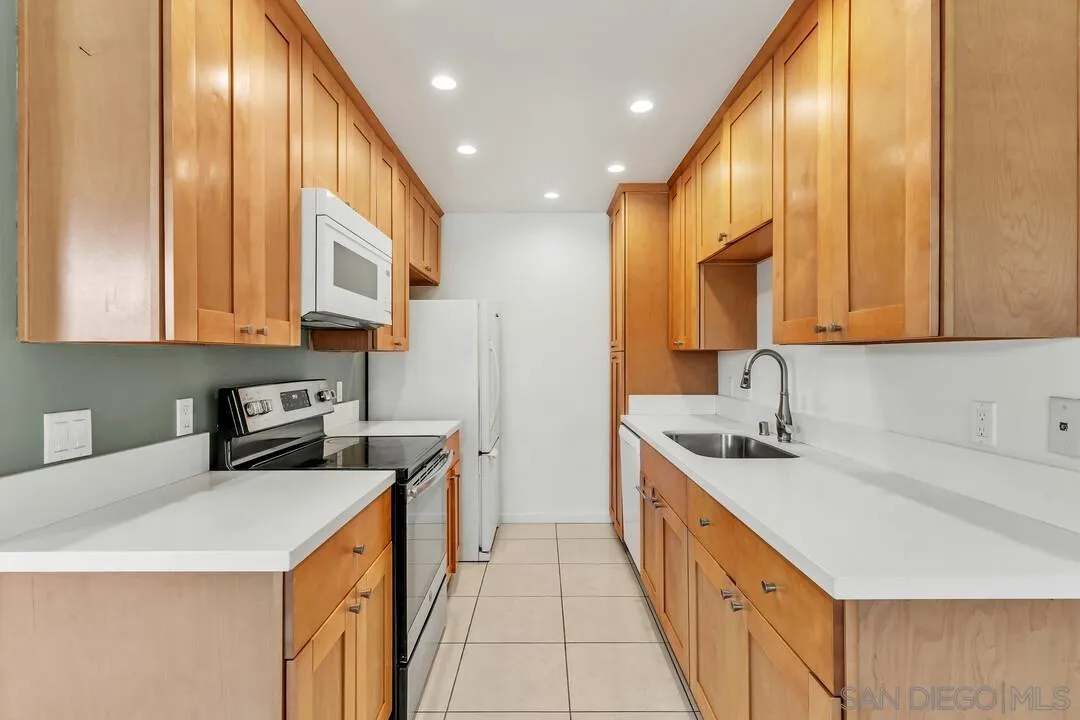 8536 Via Mallorca, Unit B La Jolla, CA 92037 - Photo 3 of 34 a kitchen with stainless steel appliances a sink a stove a refrigerator cabinets and a dining table