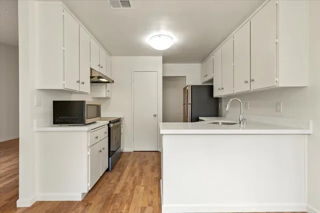 a kitchen with cabinets appliances a sink and a counter top space