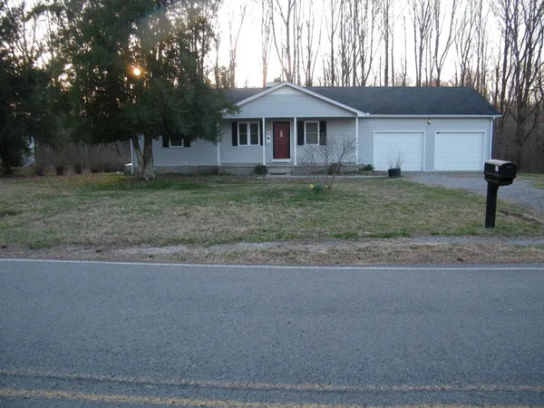 a front view of a house with a yard and trees