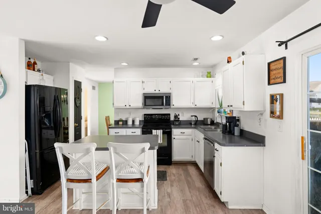 a kitchen with stainless steel appliances kitchen island granite countertop a stove top oven a sink a refrigerator with a dining table and chairs