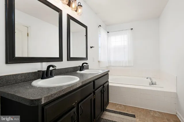 a bathroom with a sink double vanity granite tub and a mirror