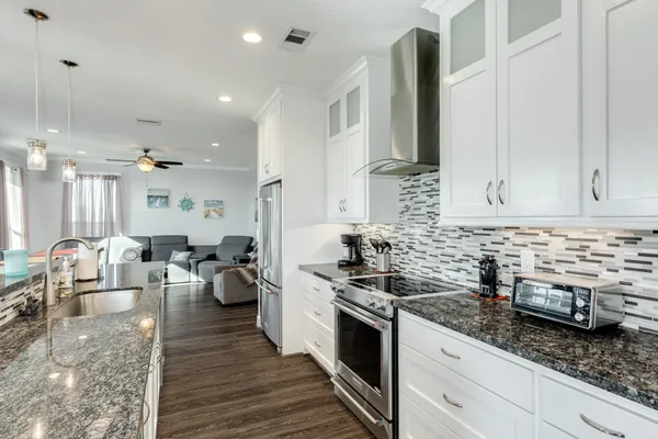 a large kitchen with kitchen island a sink stove and wooden floor