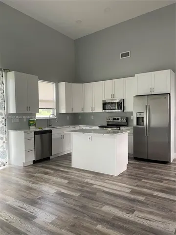 a kitchen with granite countertop a refrigerator and white cabinets