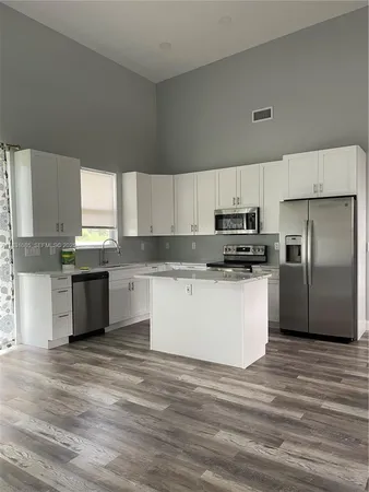 a kitchen with granite countertop a refrigerator and white cabinets