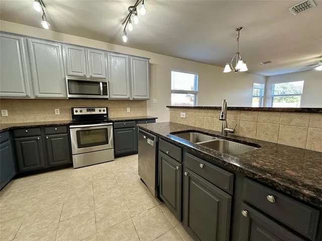 a kitchen with stainless steel appliances granite countertop a sink a stove top oven a counter space and cabinets