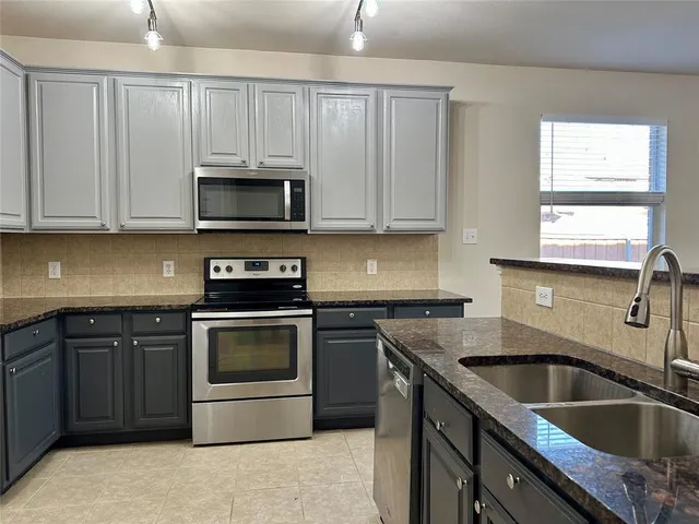 a kitchen with granite countertop a sink stainless steel appliances and cabinets
