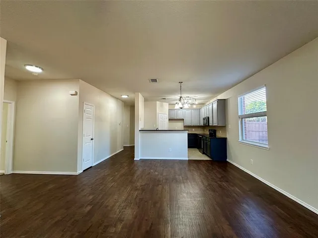 a view of kitchen and empty room with wooden floor