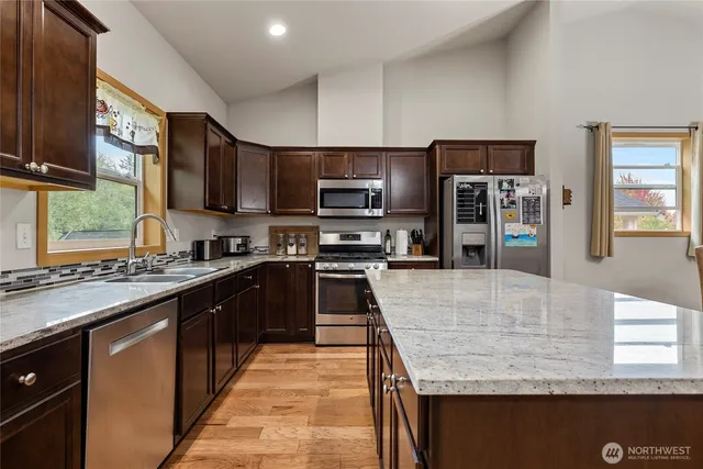 a large kitchen with granite countertop lots of counter top space a sink and appliances