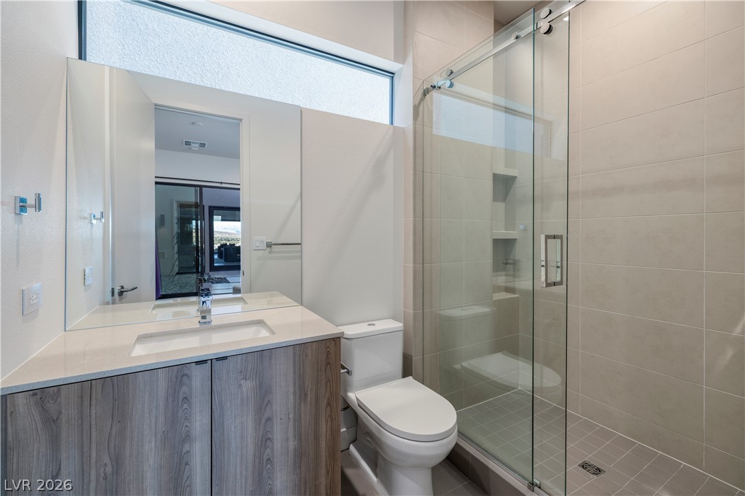 25 Falling Ridge Lane Henderson, NV 89011 - Photo 29 of 48 A well-appointed bathroom features a spacious vanity with dual sinks, sleek countertops, and a clear glass shower enclosure.