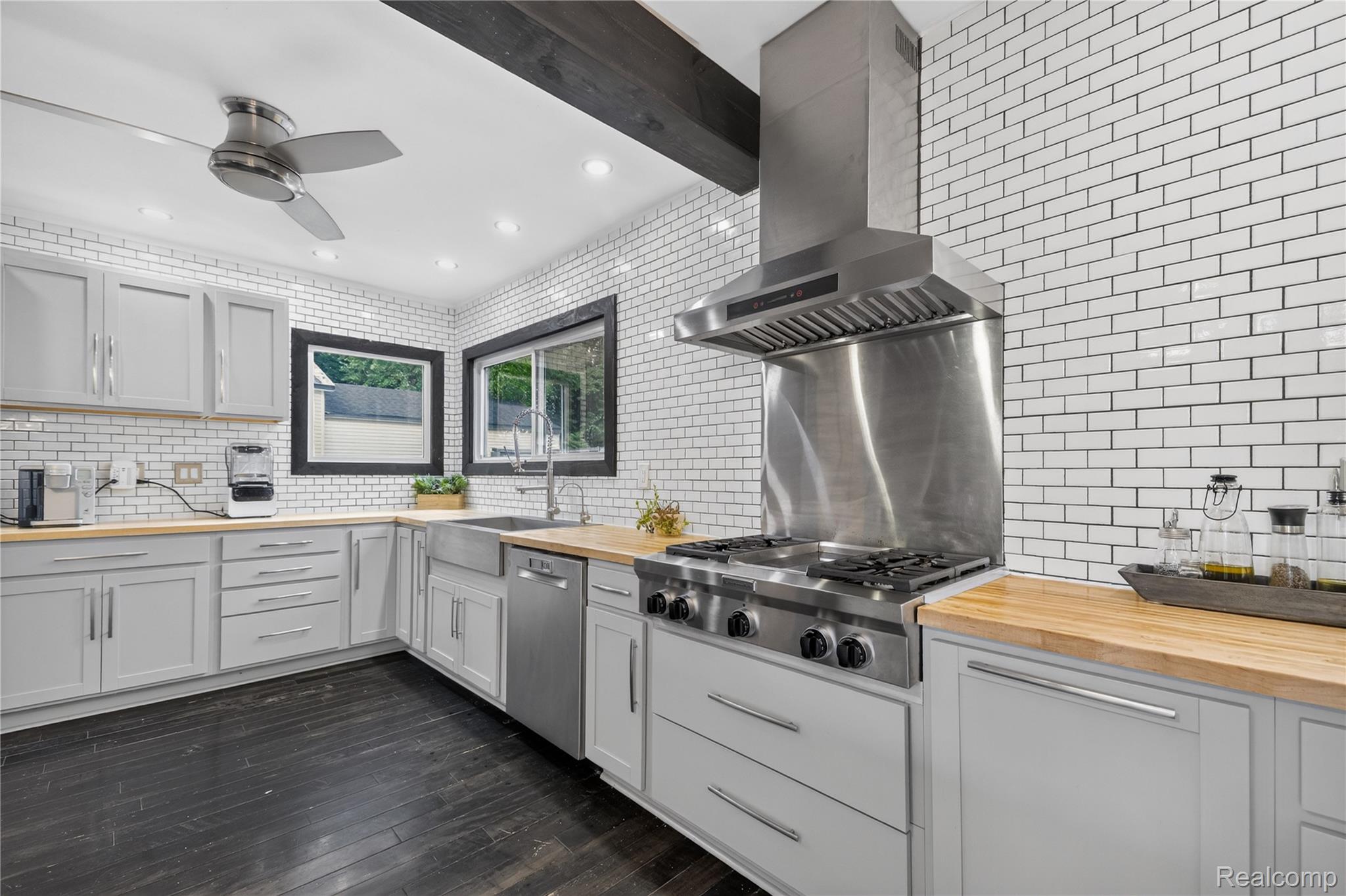 4860 Blue Bush Road Monroe, MI 48162 - Photo 11 of 59 Modern kitchen featuring a stainless steel range with a professional-grade hood, wood-finish countertops, white subway tile backsplash, and light gray cabinetry with contemporary hardware