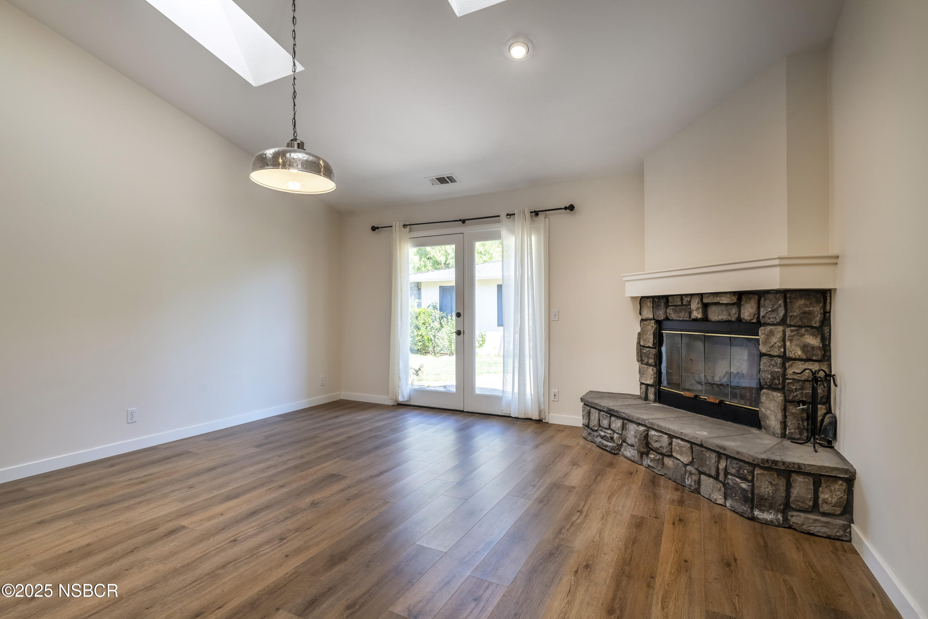 576 Pine Street, Unit A Solvang, CA 93463 - Photo 6 of 19 an empty room with wooden floor fireplace and windows