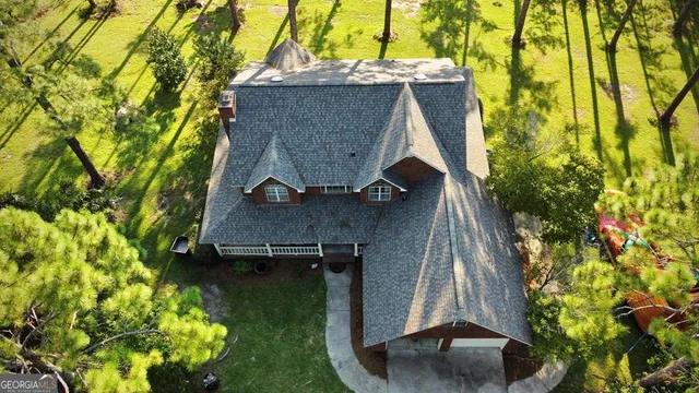 a view of swimming pool with lawn chairs and large trees