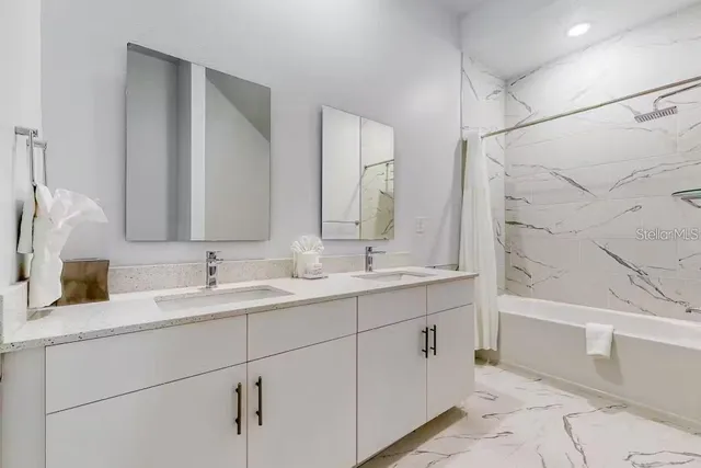 a bathroom with a double vanity sink a mirror and a bathtub