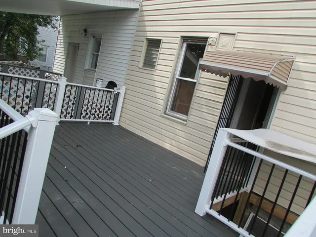 a view of a hallway with wooden floor and a bathroom