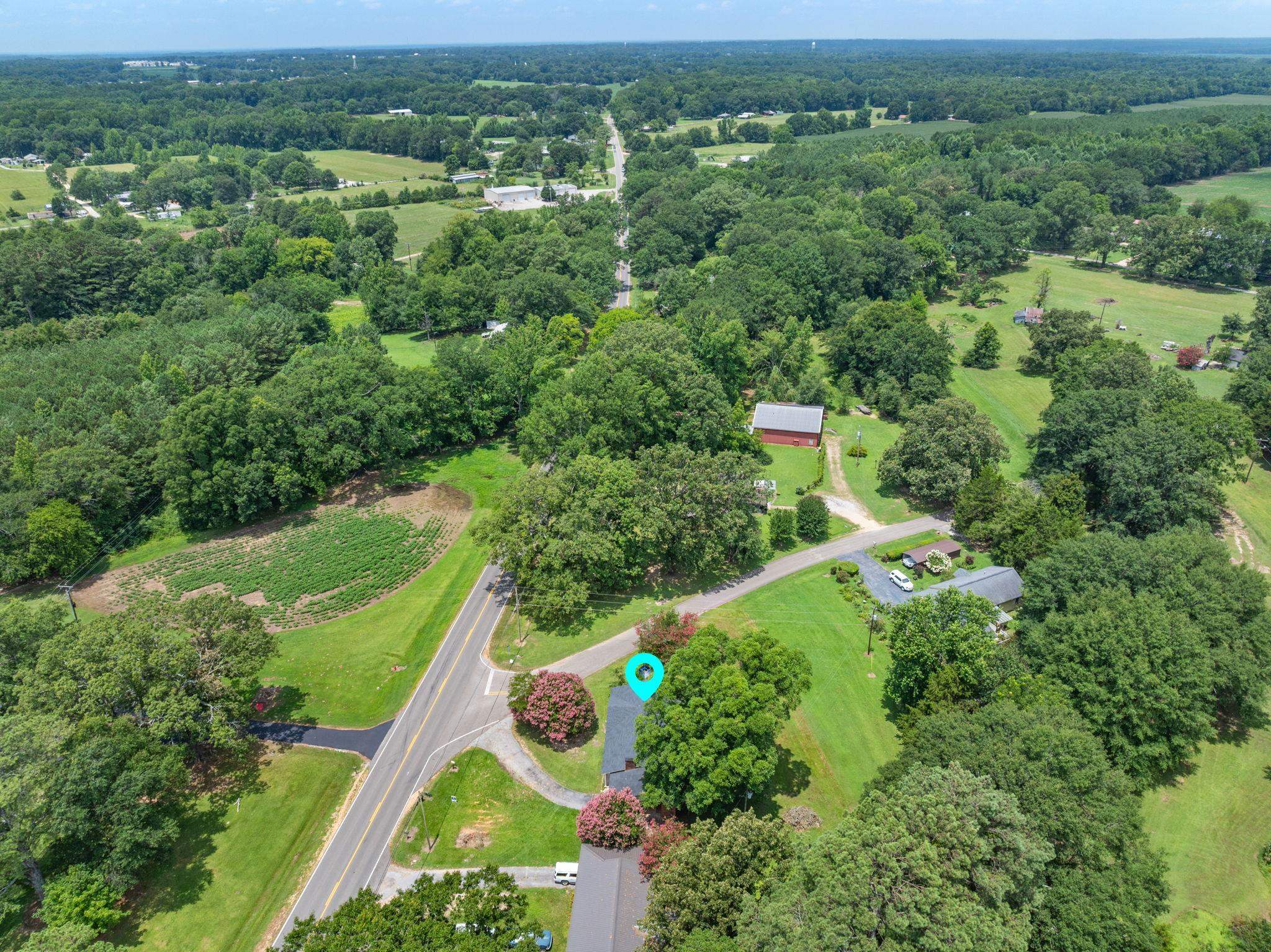 217 Red Bay Road Golden, MS 38847 - Photo 28 of 33 Sprawling property featuring a prominent red barn, mature trees, open green spaces, and an asphalt driveway