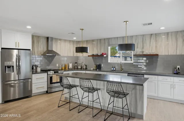 a kitchen with stainless steel appliances granite countertop a sink a stove a refrigerator cabinets and chairs