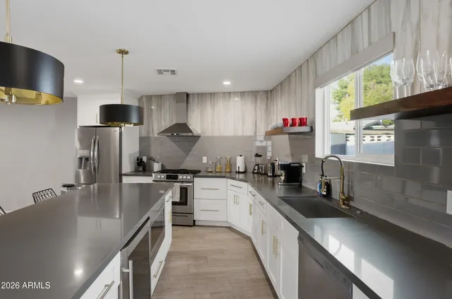 a kitchen with stainless steel appliances granite countertop a sink a stove and a refrigerator