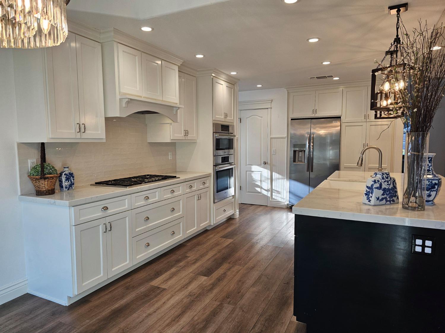 576 West Bedford Avenue Clovis, CA 93611 - Photo 17 of 79 a kitchen with stainless steel appliances kitchen island granite countertop a sink dishwasher a refrigerator and white cabinets with wooden floor