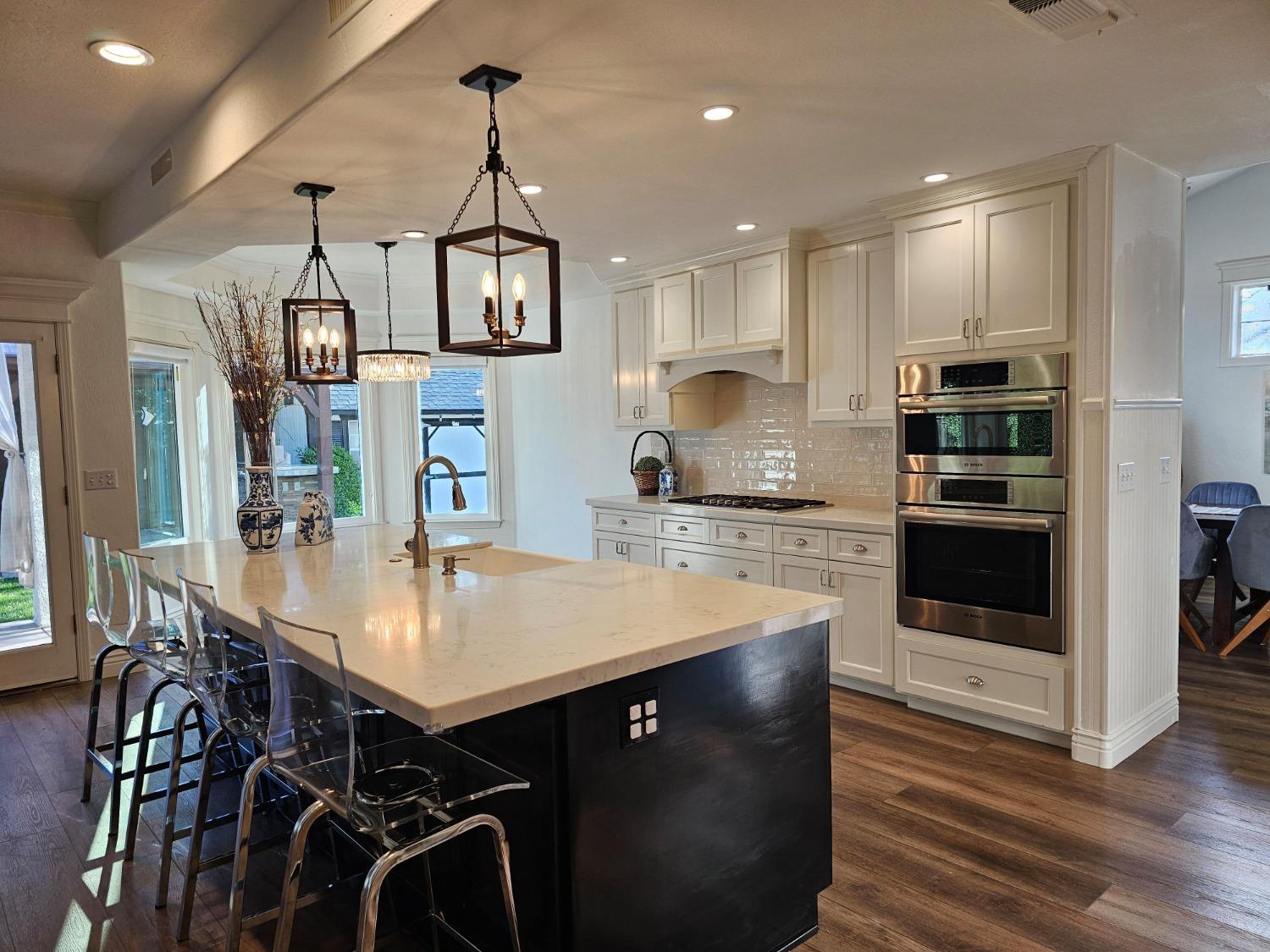 576 West Bedford Avenue Clovis, CA 93611 - Photo 21 of 79 a kitchen with stainless steel appliances kitchen island granite countertop a stove a refrigerator a sink a dining table and chairs with wooden floor