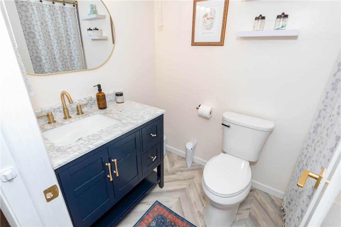 4102 Ridgetop Drive Bellbrook, OH 45305 - Photo 27 of 33 This bright bathroom features a blue vanity with a white countertop and gold fixtures.
