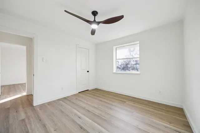 an empty room with wooden floor and ceiling fan